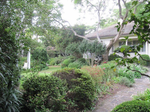 The garden at Eryldene in Gordon, with clipped shrubs, a path and the house beyond